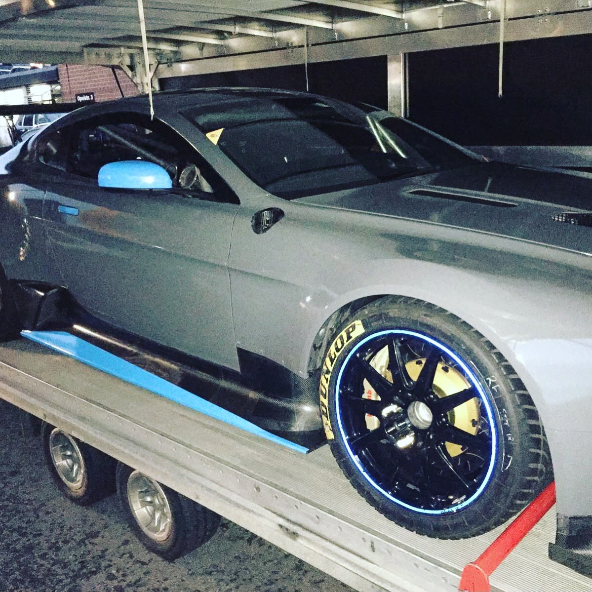 Nahaufnahme des Aston Martin Vantage GT Rennwagens mit Rennreifen und Rennfahrwerk auf dem Autotransporter in der Opelstraße Konstanz