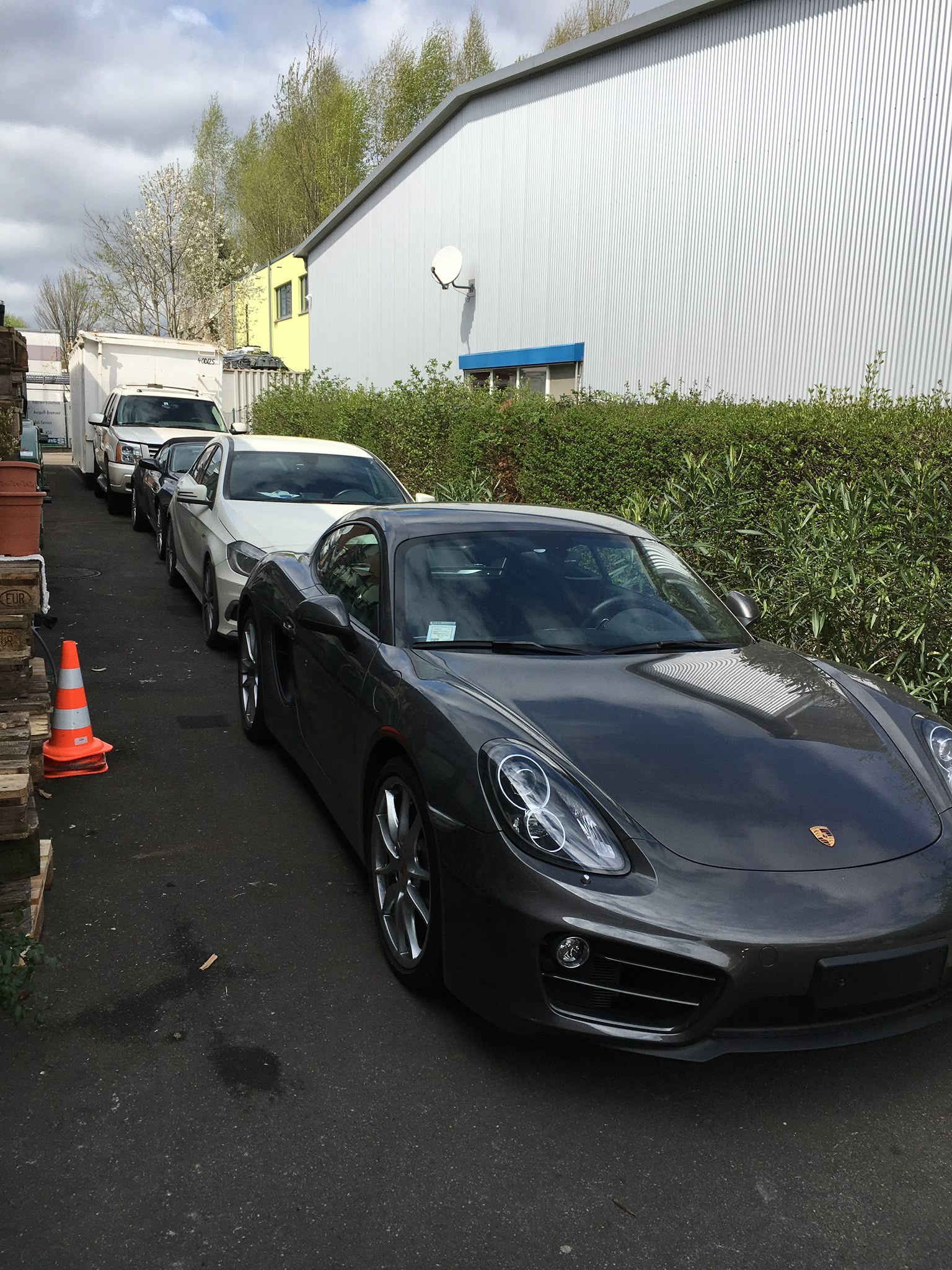 Grauer Porsche Cayman und weitere Kundenfahrzeuge auf dem Gelände der Lieferadresse Konstanz im Industriegebiet Opelstraße